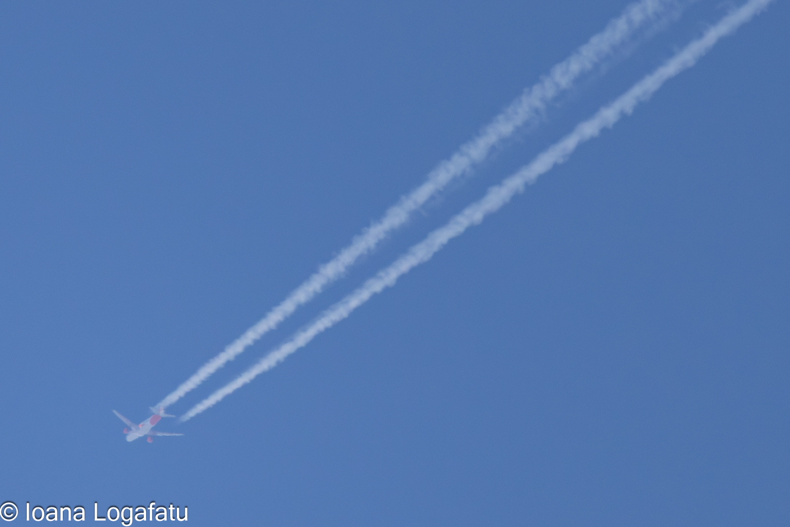 Contrails tracing the clear blue sky above